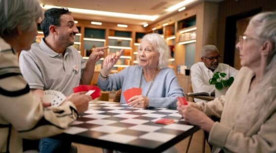 Une résidente seniors joue aux cartes avec un coordinateur Nohée